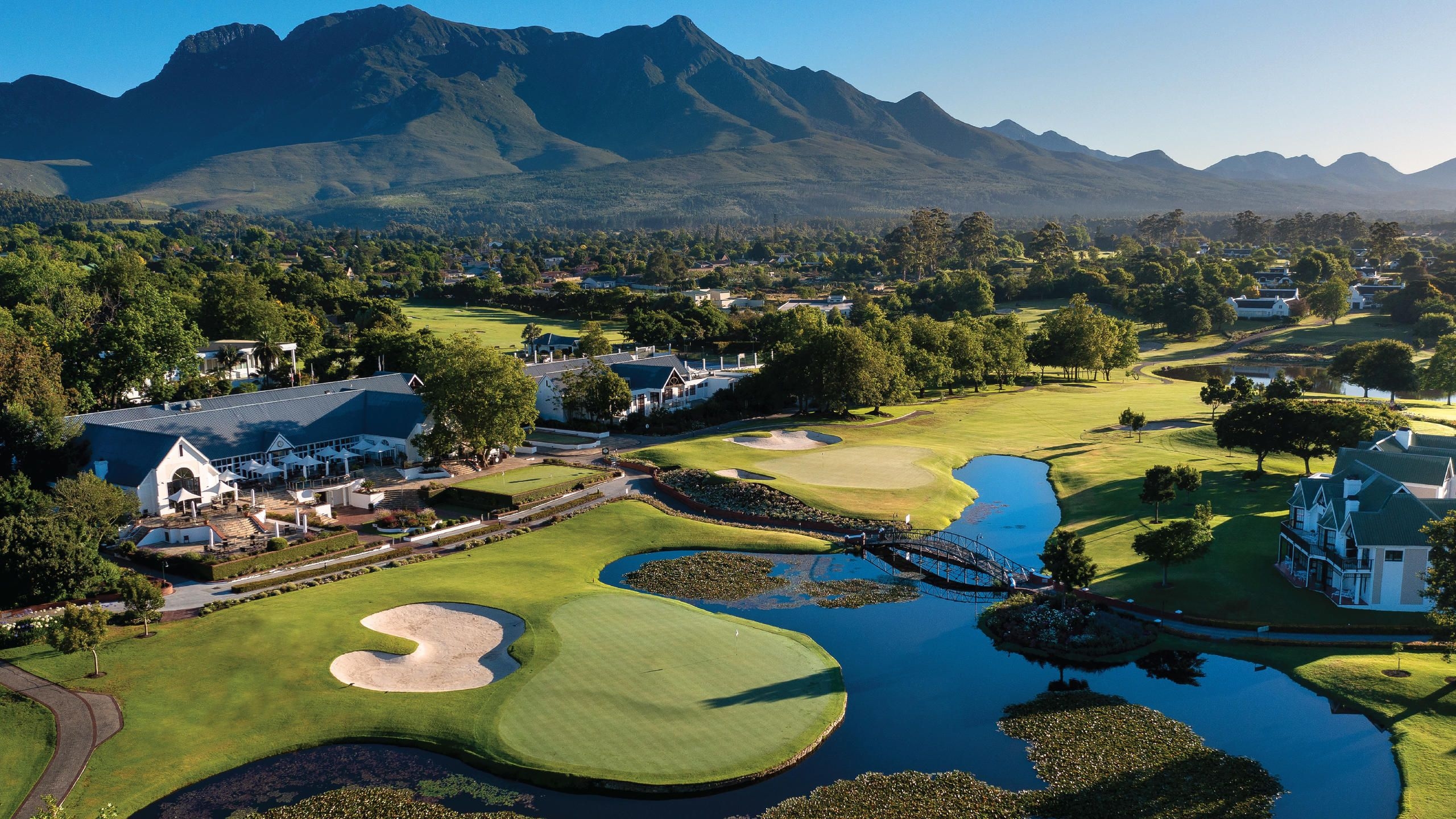 Fancourt Montagu Golf Course with a manicured green, rolling fairways, trees and mountains in the distance.