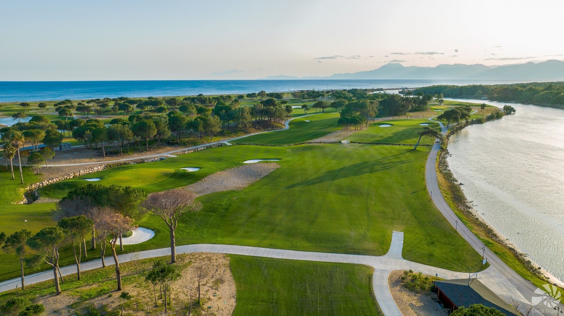View over Aspendos Golf Course with manicured fairways, greens, and surrounding trees under a clear sky