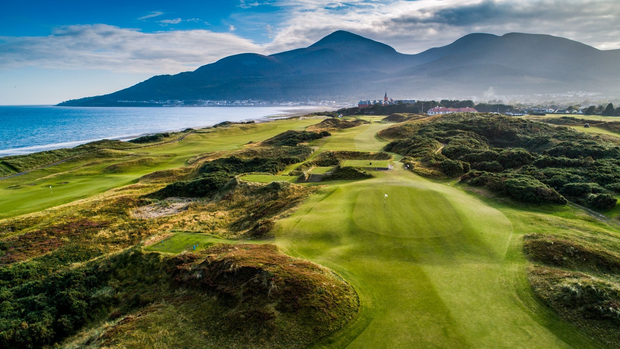 A scenic view of the Royal County Down golf course, showcasing its lush green fairways and the surrounding natural landscape.