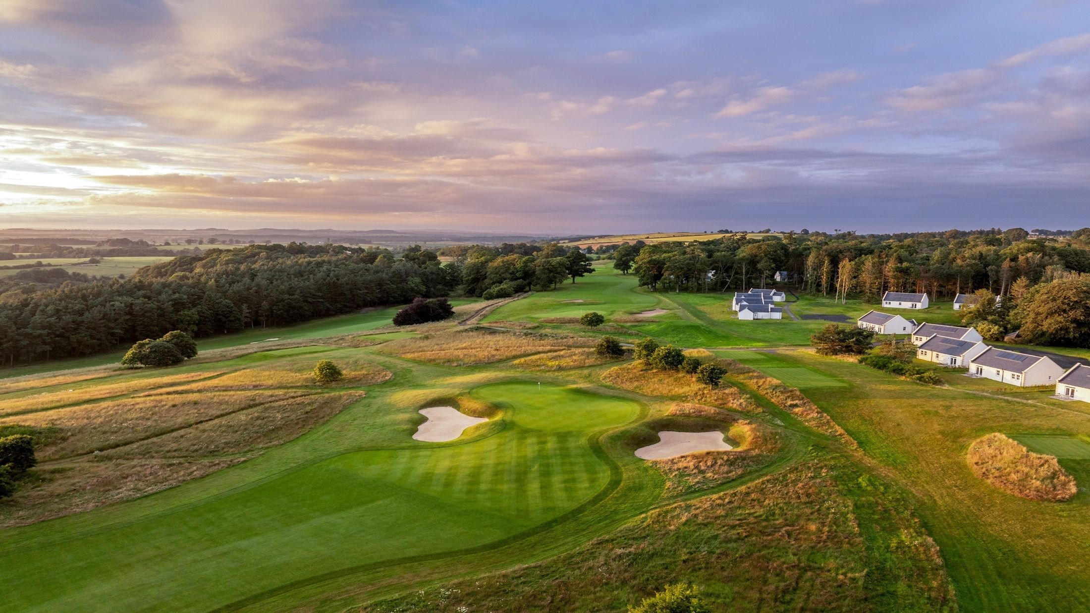 View of Roxburghe Golf Club course with manicured fairway, greens, and surrounding trees under a clear sky