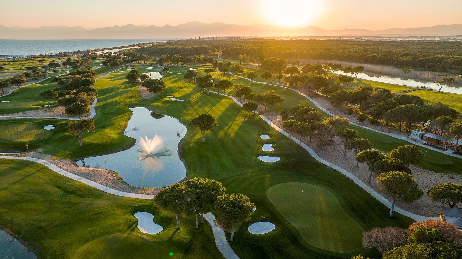 Wide view of Olympus Golf Course with manicured fairways, greens, and surrounding trees under a clear sky