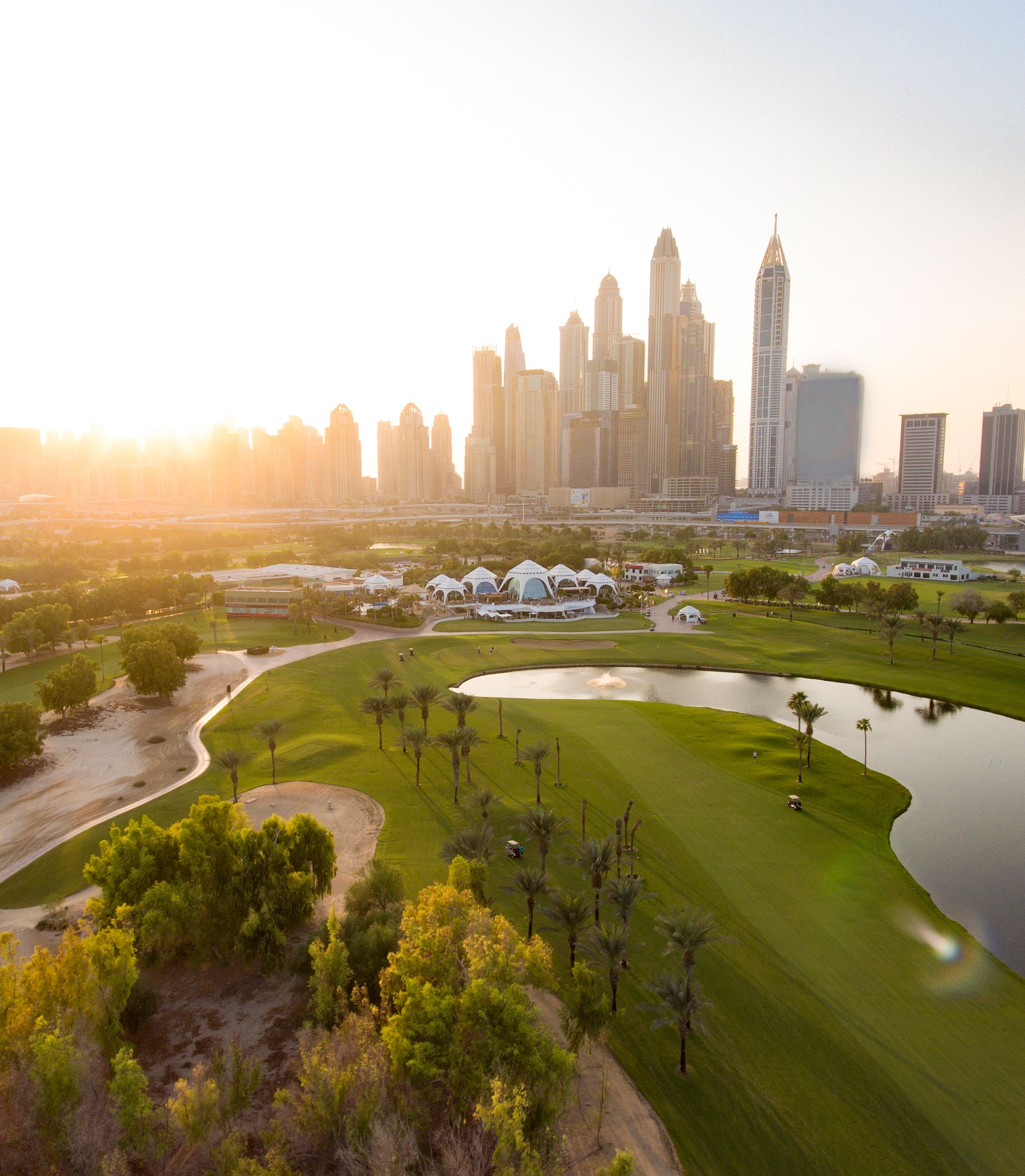 Wide view of Majilis Golf Course with manicured fairways, bright green grass, and surrounding desert landscape under a clear sky