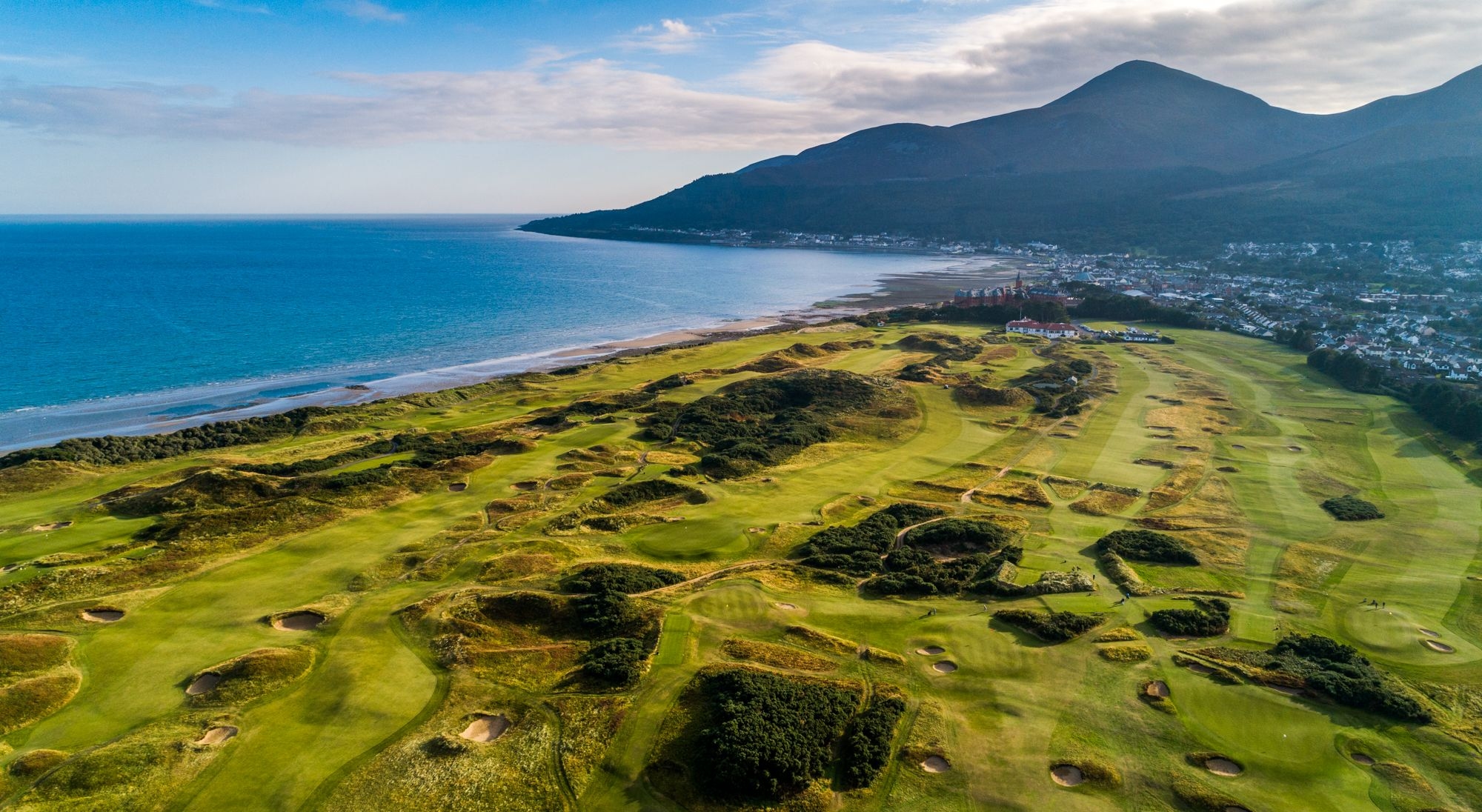 A scenic view of the Royal County Down golf course, showcasing its lush green fairways and the surrounding natural landscape.