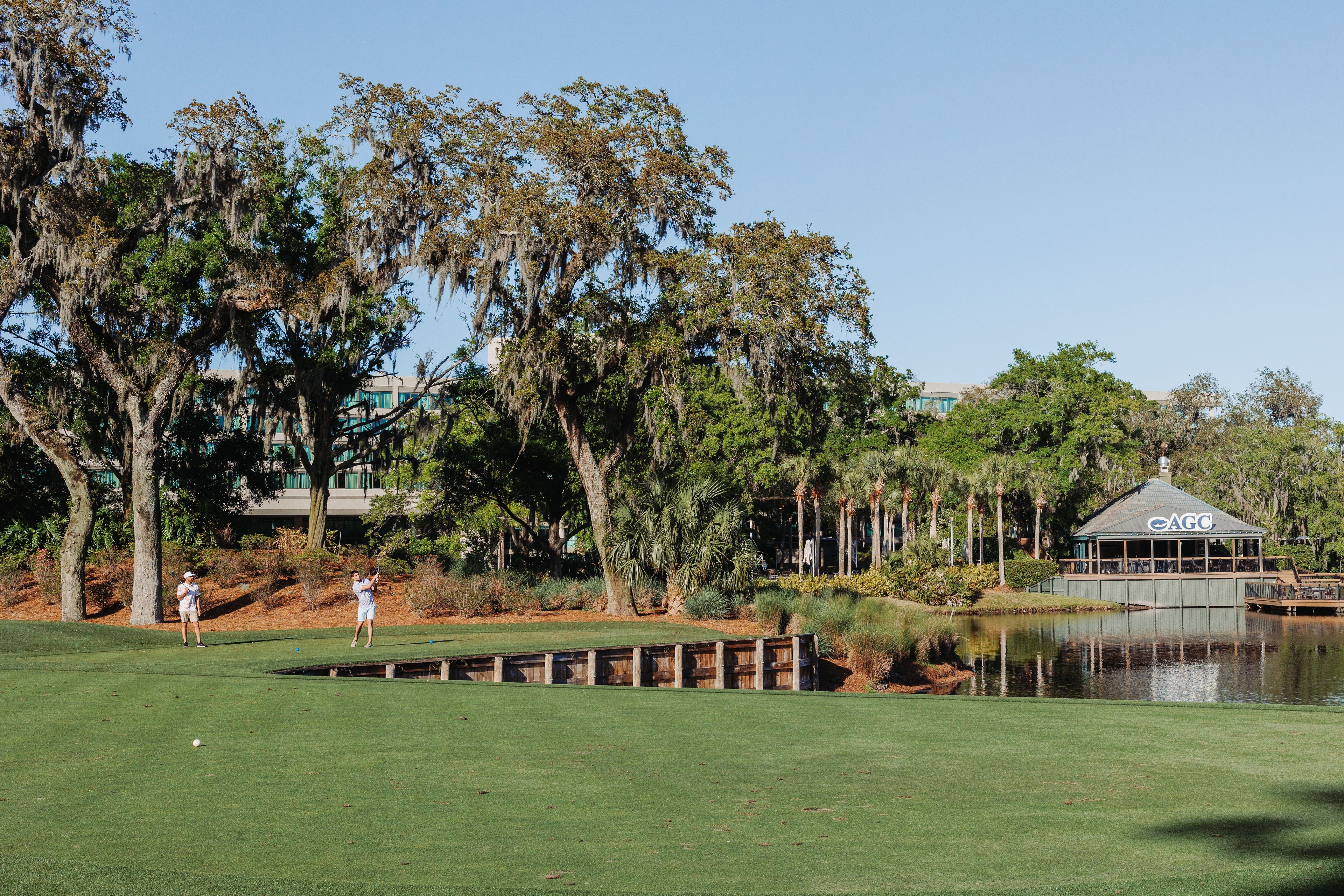 Golf fairway at Sawgrass with neatly mowed grass, sand bunkers, and a calm lake in the background under a clear sky