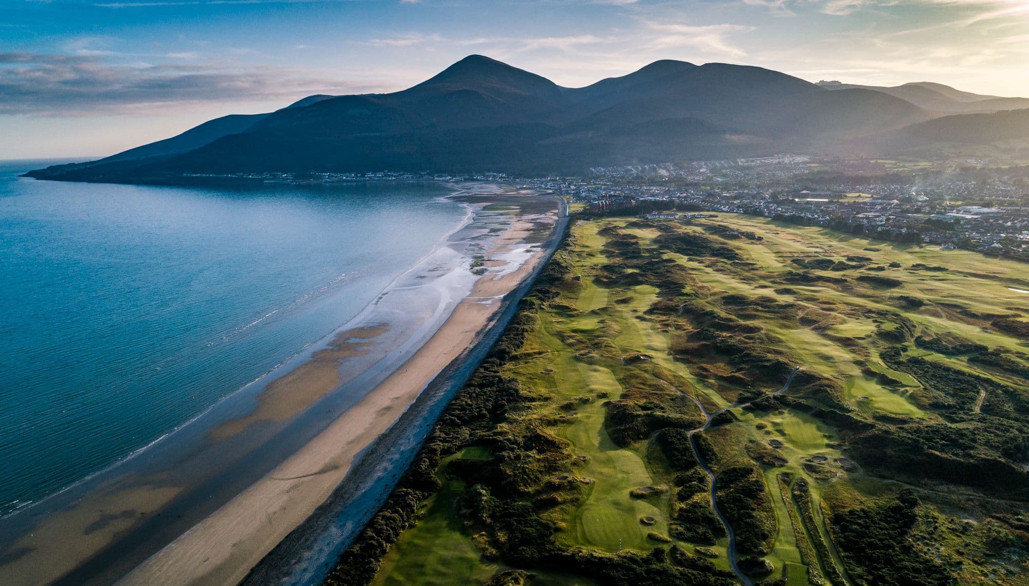 A scenic view of the Royal County Down golf course, showcasing its lush green fairways and the surrounding natural landscape.