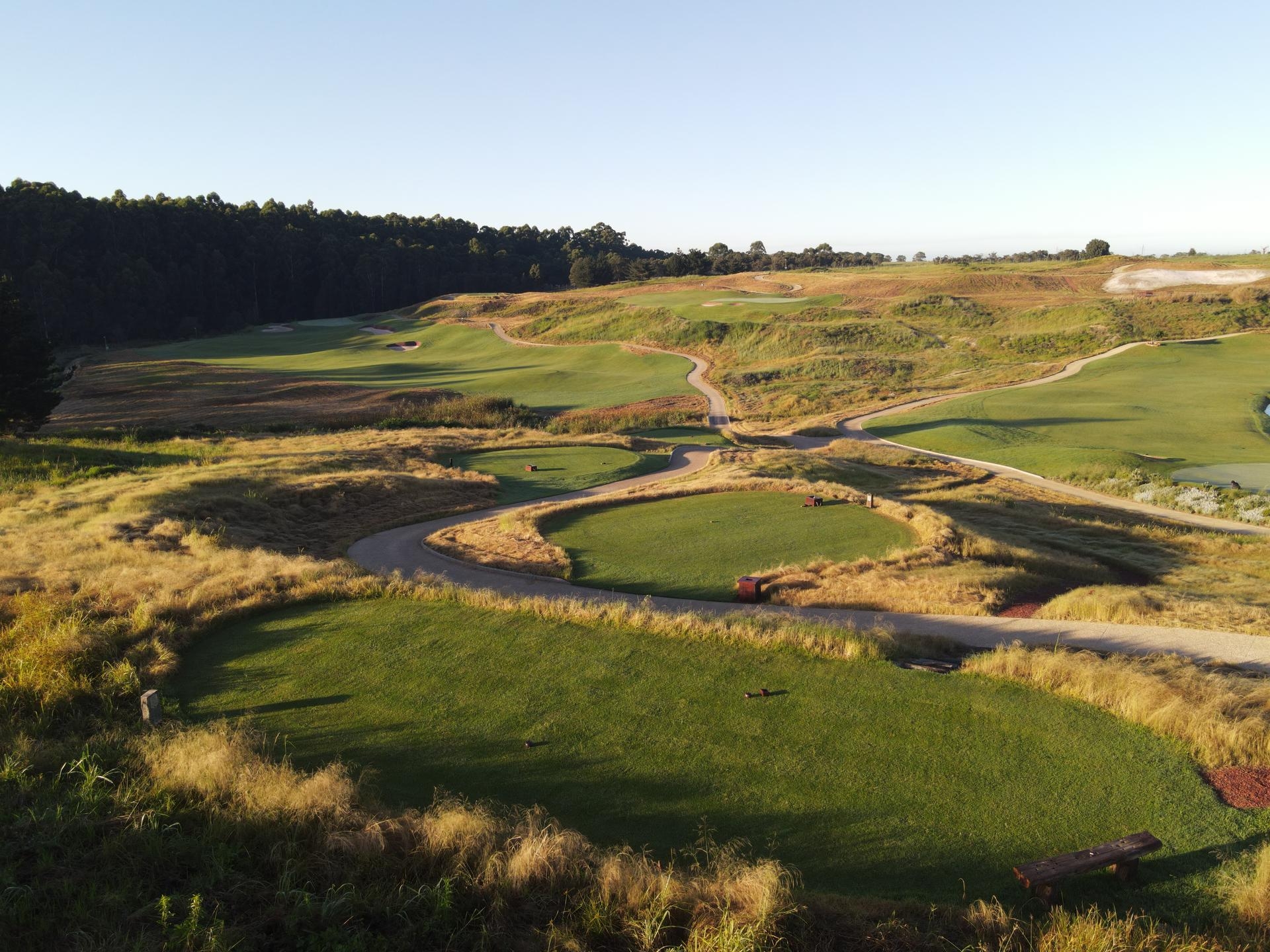 Aerial view of the Fancourt golf course, with rolling fairways, greens, trees and mountains in the distance.