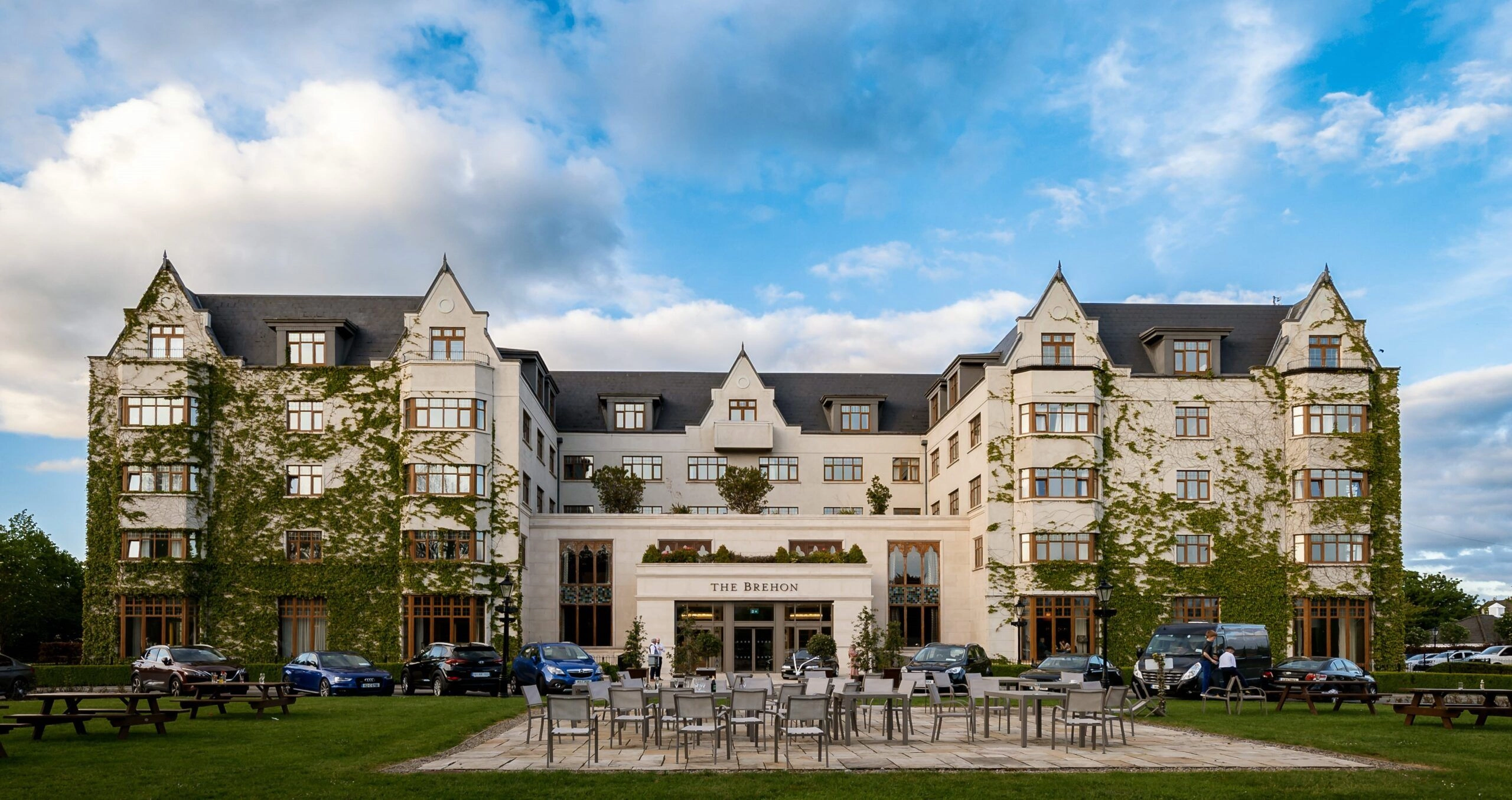 Exterior view of The Brehon hotel in Killarney, a modern multi-story building with large windows, set against a scenic Irish landscape